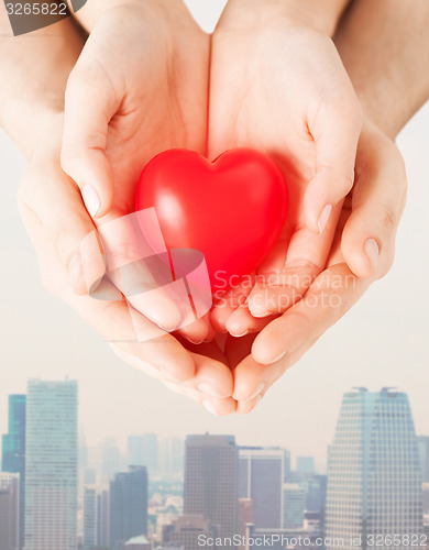 Image of close up of couple hands holding red heart