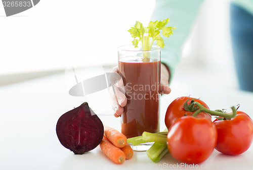 Image of close up of woman hands with juice and vegetables