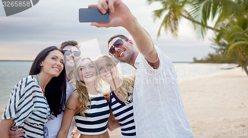 Image of friends on beach taking selfie with smartphone