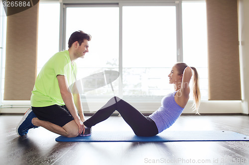 Image of woman with personal trainer doing sit ups in gym