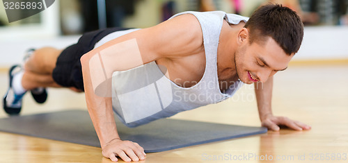 Image of smiling man doing push-ups in the gym