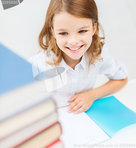 Image of smiling little student girl with many books