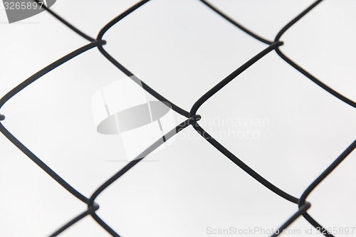 Image of close up of mesh fence over gray sky