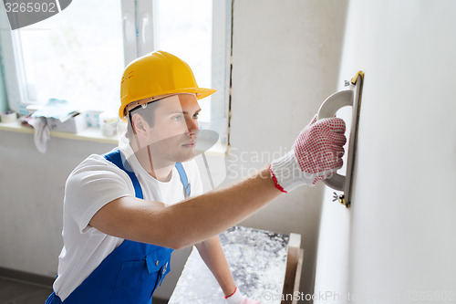 Image of smiling builder with grinding tool indoors