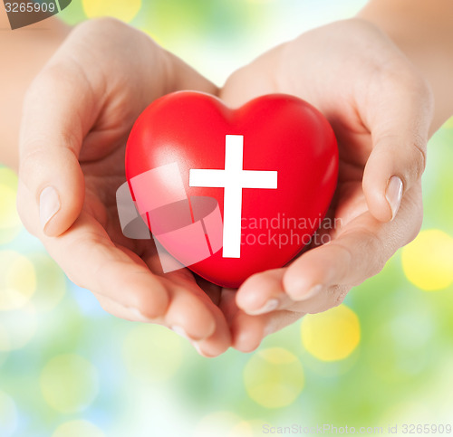 Image of close up of hands holding heart with cross symbol