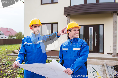 Image of smiling builders with blueprint pointing finger