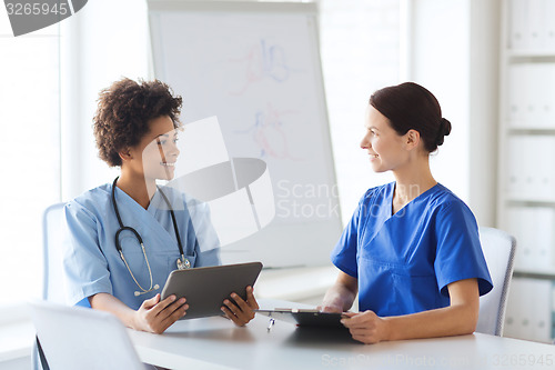 Image of happy doctors with tablet pc meeting at hospital