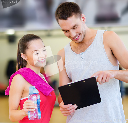 Image of smiling male trainer with woman in the gym