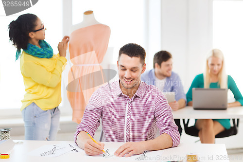 Image of smiling fashion designers working in office