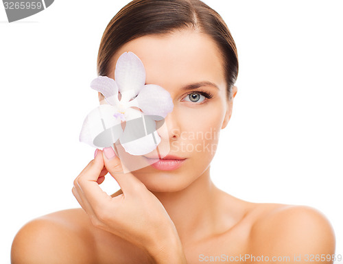 Image of relaxed woman with orchid flower over eye
