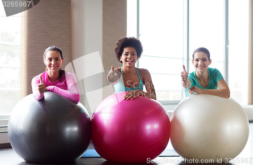 Image of group of smiling women with exercise balls in gym