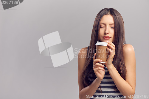 Image of Woman drinking hot drink from disposable paper cup