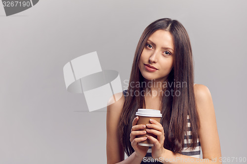 Image of Woman drinking hot drink from disposable paper cup