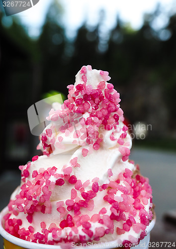 Image of Closeup of soft serve ice cream with fresh pink frizzle outdoors