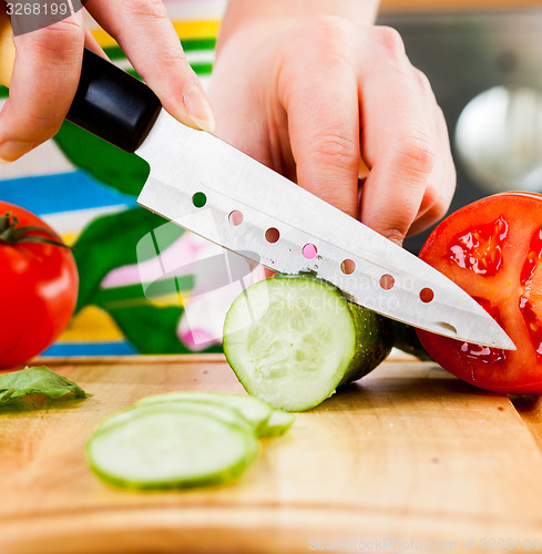 Image of Woman\'s hands cutting cucumber