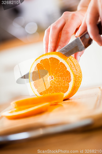 Image of Woman\'s hands cutting orange