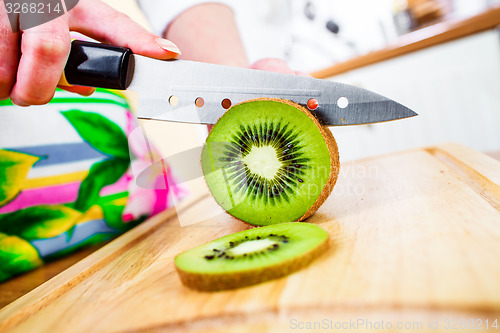 Image of Woman\'s hands cutting kiwi