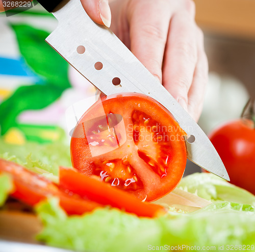 Image of Woman\'s hands cutting tomato