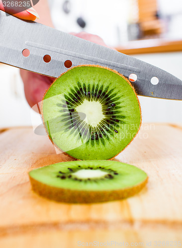 Image of Woman\'s hands cutting kiwi