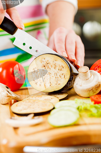 Image of Woman\'s hands cutting aubergine eggplant