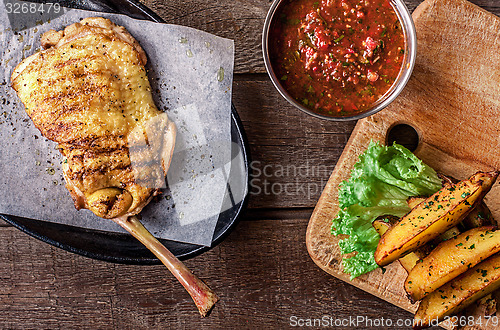 Image of Fried chicken meat on the bone, potato wedges, lettuce 