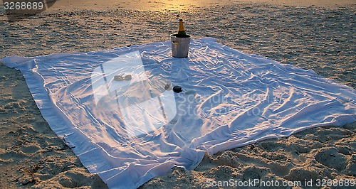 Image of champagne and sunglasses on the beach at sunset