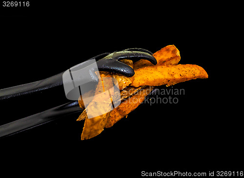 Image of Closeup of black plastic tong holding fresh fried potatoes isola