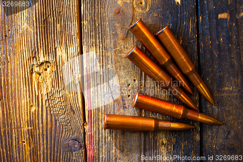 Image of five rifle cartridges on wooden surface