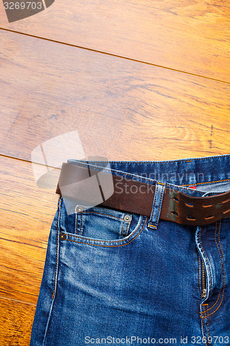 Image of Aged blue jeans with a leather belt 