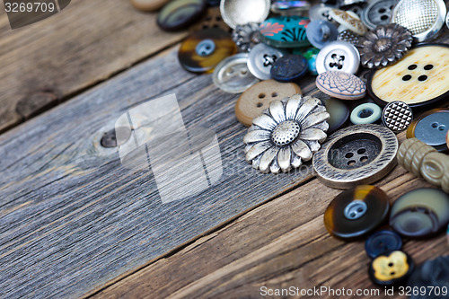 Image of buttons in large numbers scattered on aged wooden boards