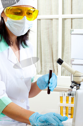 Image of doctor looking at a test tube of dark solution