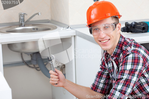 Image of smiling plumber near the kitchen sink