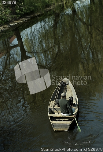 Image of Man and dog  in boat on river
