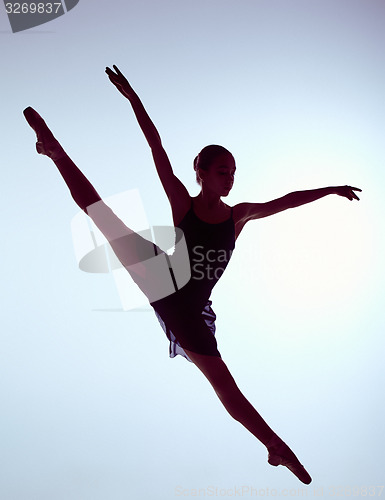 Image of Beautiful young ballet dancer jumping on a gray background. 