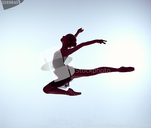 Image of Beautiful young ballet dancer jumping on a gray background. 