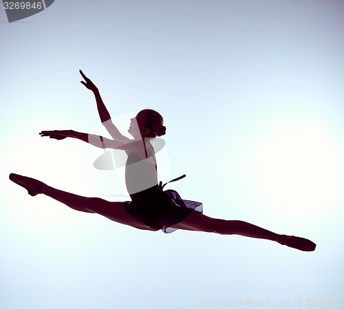 Image of Beautiful young ballet dancer jumping on a gray background. 