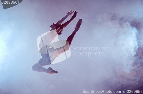 Image of Beautiful young ballet dancer jumping on a lilac background. 