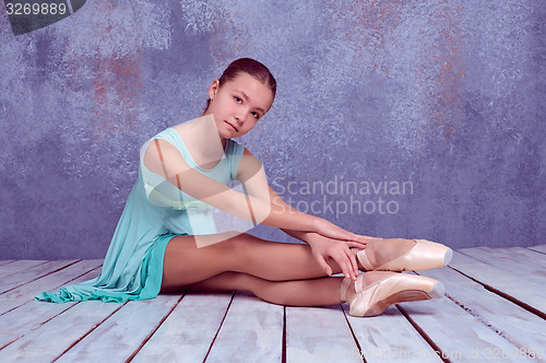 Image of young ballerina sitting on wooden floor