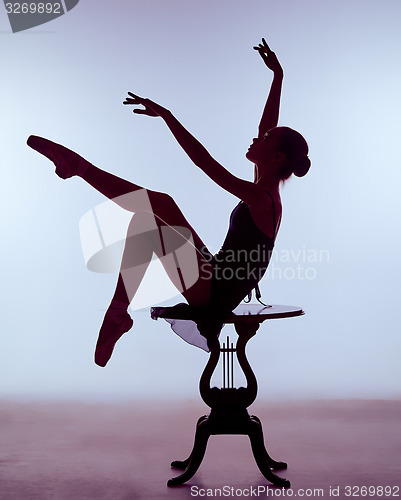Image of young ballerina sitting on wooden chair