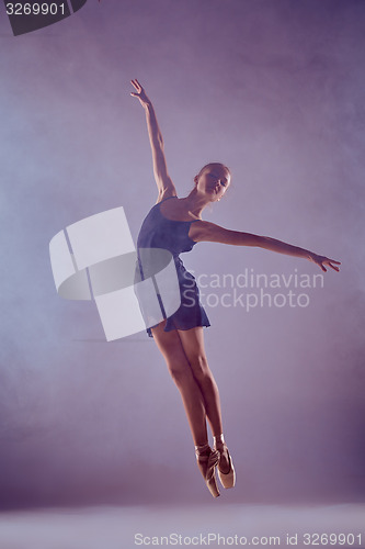 Image of Beautiful young ballet dancer jumping on a lilac background. 