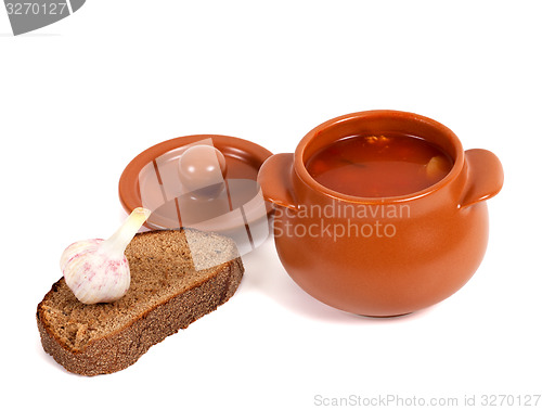 Image of Borsch in clay pot with bread and garlic