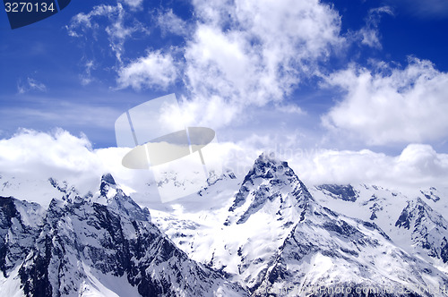 Image of Snowy mountains in clouds at sun day