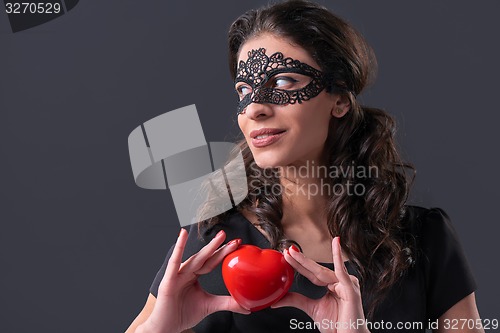 Image of Woman wearing black mask holding heart shape