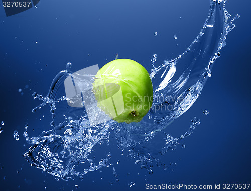 Image of Green apple with water splash, on blue water