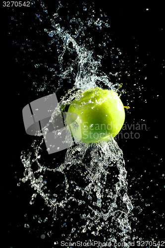 Image of Green apple with water splash, on black