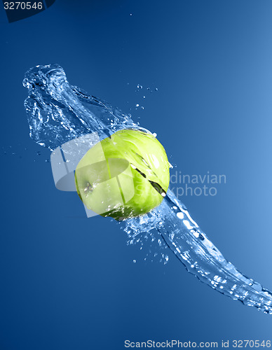 Image of Green apple with water splash, on blue water