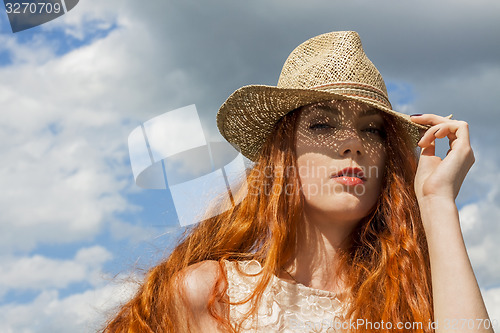 Image of Gorgeous Woman in Hat on Cloudy Sky background