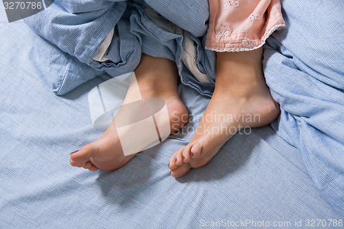 Image of Bare Feet of a Young Woman on Blue Bed