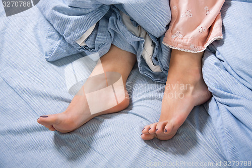 Image of Bare Feet of a Young Woman on Blue Bed