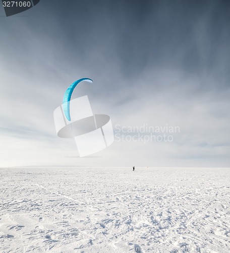 Image of Kiteboarder with blue kite on the snow